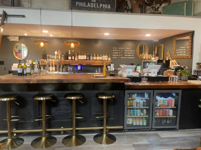Modern bar interior at Mercantile 1888 with stocked shelves, bar stools, and a fridge displaying a variety of cannabis beverages alongside other drinks.