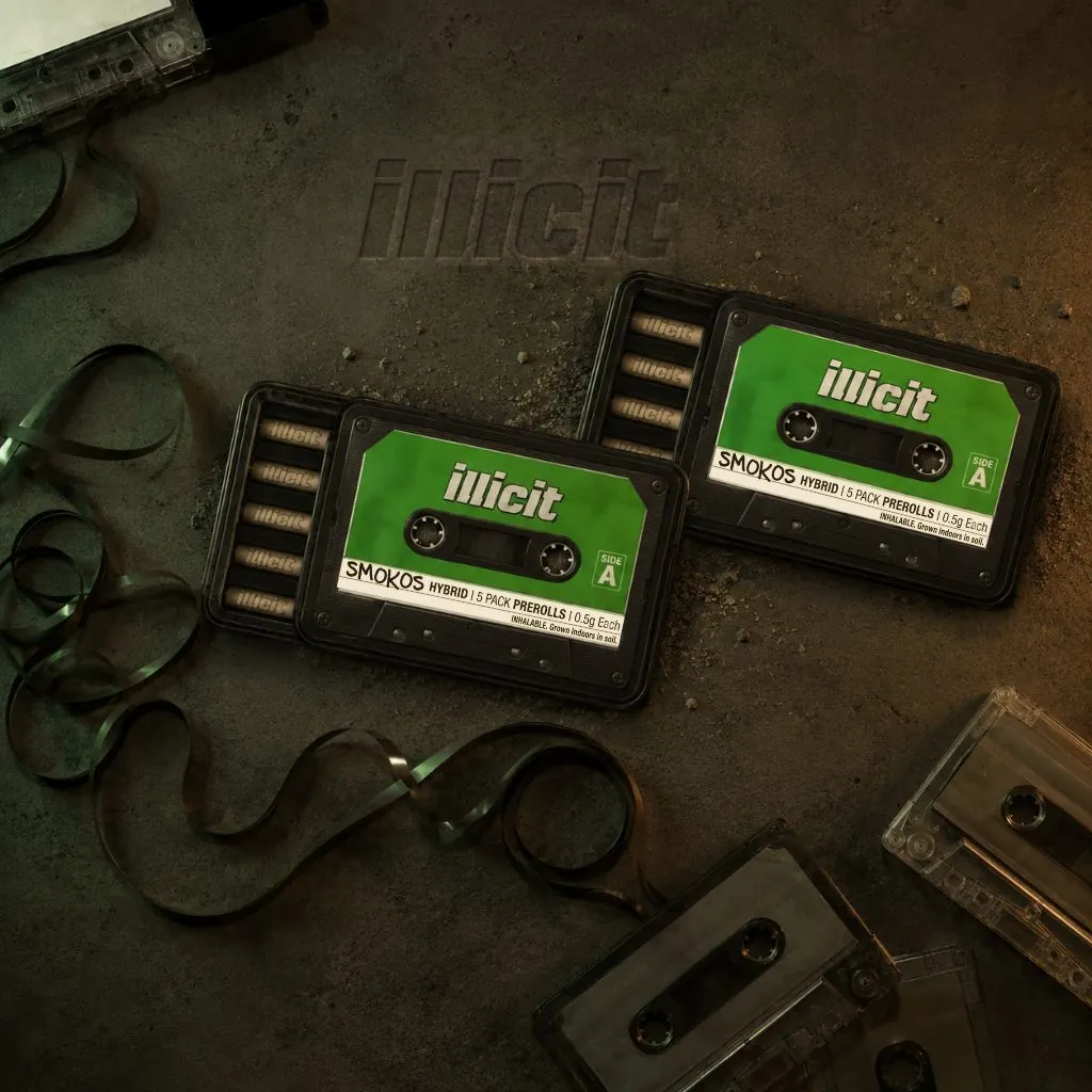 Two black Illicit Smokos tins on concrete, trays slid open showing five 0.5g pre-rolls each with cassette tapes in the corners for the product highlights of Illicit Gardens Cannabis in Franklin Park