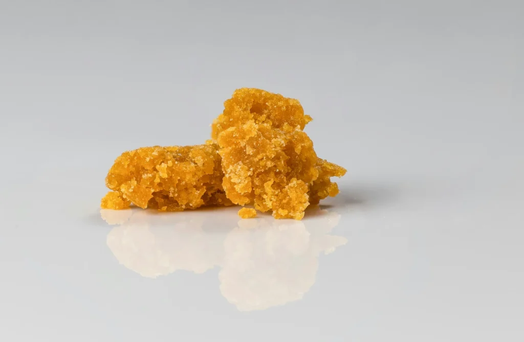 Crumbly, crystalline sugar-textured cannabis concentrate on a reflective surface